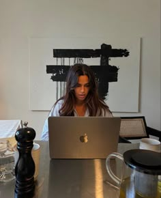 a woman sitting at a table with a laptop computer in front of her on the desk