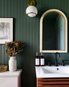 a white sink sitting under a bathroom mirror next to a wooden cabinet and counter top