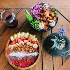 a wooden table topped with two bowls filled with fruit and veggie salads