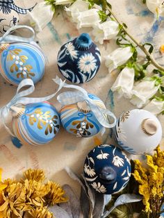 some blue and white ornaments are sitting on a table with yellow flowers in the background