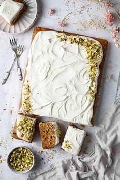 a cake with white frosting and nuts on it next to two slices of cake