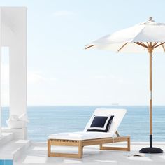 an umbrella and lounge chair on a patio overlooking the ocean