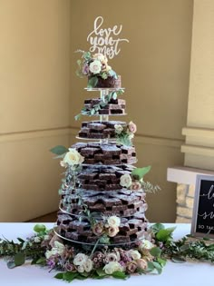 a wedding cake made out of chocolate waffles and flowers on a white table