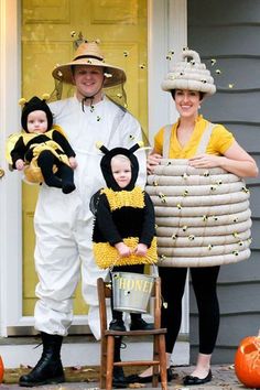 a man and woman dressed up as bee costumes with two children in front of a house