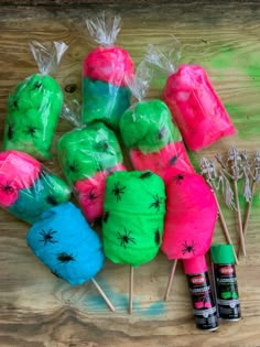 some green, pink and blue lollipops are sitting on a wooden table