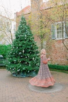 a woman standing in front of a christmas tree