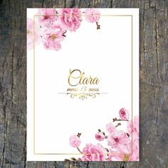 a wedding card with pink flowers and gold foil lettering on the front, sitting on top of a piece of wood