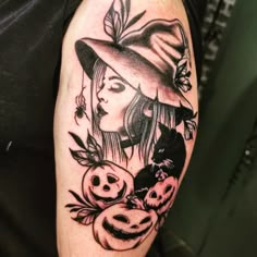 a woman wearing a witches hat with pumpkins on her arm