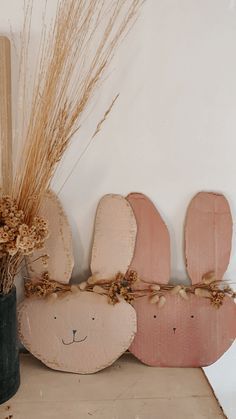 two wooden bunny ears are next to a vase with dried grass in it on a shelf