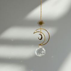 the sun and moon is hanging from a gold chain with a clear crystal ball on it