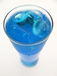 a glass filled with blue liquid on top of a table