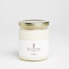 an old pine candle is shown on a white surface with a gold lid and the label reads, sunny days