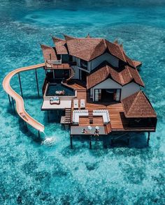 an aerial view of a house on stilts in the middle of clear blue water