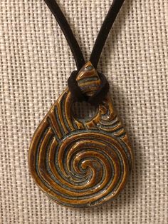 "this beautiful swirly designed teardrop pendant is on an 18\" brown suede necklace, but the fit will be tighter because the pendant is wrapped." Handmade Collectible Teardrop Pendant Necklace, Brown Spiral Jewelry As A Gift, Unique Metal Teardrop Pendant Necklaces, Brown Teardrop Necklace For Gift, Brown Teardrop Necklace For Gifts, Ceramic Pendants, Clay Necklaces, Brown Spiral Necklace For Gifts, Adjustable Brown Teardrop Jewelry