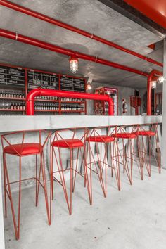 red bar stools sit at the end of a long counter in an industrial restaurant