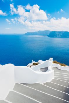 the stairs lead down to an ocean view with blue sky and clouds in the background