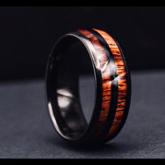 a wooden ring with black and brown inlays on the inside, sitting on a gray surface