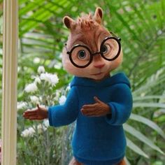 a toy squirrel with glasses and a blue sweater is standing in front of a window