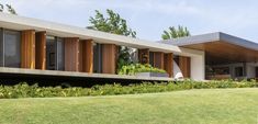 a modern house with large windows and wooden shutters on the outside, in front of green grass