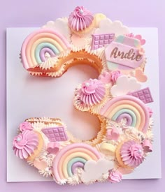 the number 5 made out of cupcakes is decorated with pastel rainbows and clouds