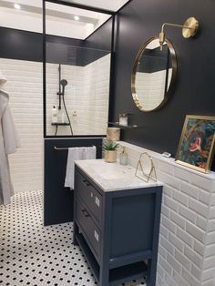 a bathroom with black and white tile, gold accents and a shower head mounted on the wall