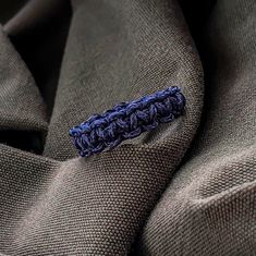 a close up of a tie with a blue crochet piece on the end