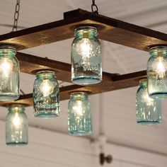 mason jar chandelier hanging from wooden beam with light bulbs on top and bottom