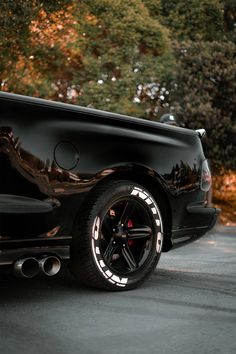 a black car parked in front of some trees