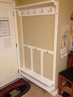 a white coat rack sitting in the corner of a room next to a door with writing on it