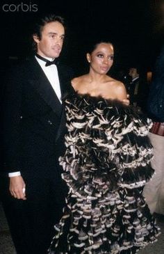 a man in a tuxedo standing next to a woman wearing a black and white dress