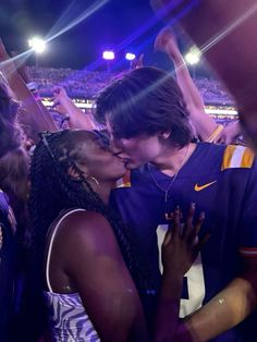 two people kissing each other at a sporting event