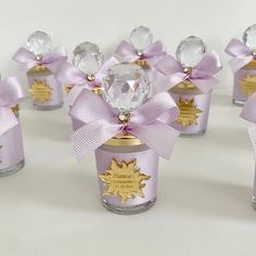 several small glass jars with bows and jewels on them, all decorated in gold foil