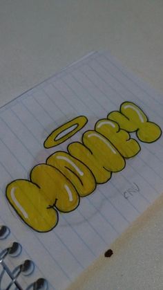 a spiral notebook with the word cookie written in yellow on it and two silver spoons next to it