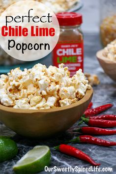 a bowl filled with popcorn next to chili and limes