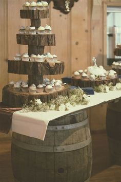 a table topped with cupcakes on top of wooden barrels