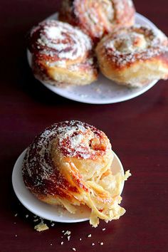 two white plates topped with powdered sugar covered donuts