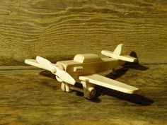 a toy airplane sitting on top of a wooden table next to a wood plank wall