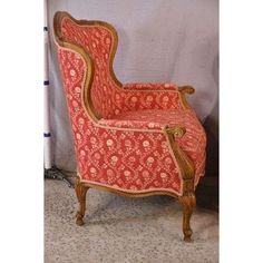 an old fashioned chair is upholstered with red fabric and gold trimmings