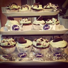 cupcakes are displayed on three tiered trays with chocolate and white frosting