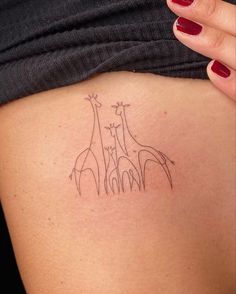 a woman's back with a tattoo of giraffes on her left side