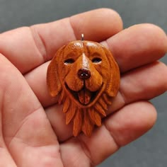 a hand holding a wooden brooch with a dog's face on it