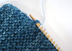 a blue knitted hat with a wooden knitting needle