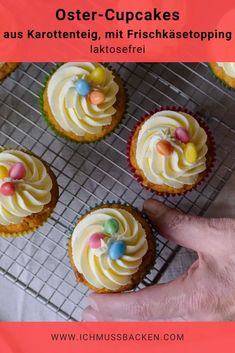 an image of cupcakes with white frosting and candies on top that are sitting on a cooling rack