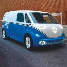 a blue and white vw bus parked in front of a brick building