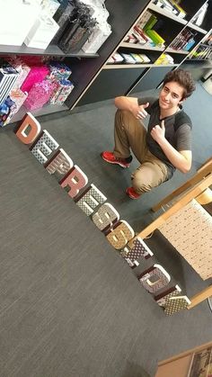 a young man sitting on the floor in front of a sign