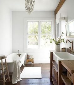 a bath room with a tub a sink and a chandelier hanging from the ceiling