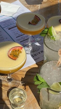 several different types of cocktails on a table with papers and drinks in glasses next to them