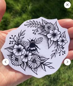 a hand holding a sticker with flowers and a bee on it's side