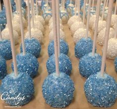 blue and white cake pops are lined up on a table