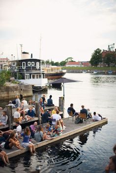 many people are sitting on the dock by the water